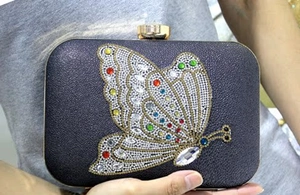 Detail of evening clutch with crystal butterfly embellishment and gold metal clasp