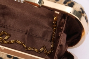 Macro detail of leopard print evening clutch with gold chain and silk interior