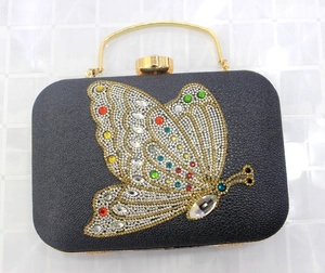 Detail of black evening clutch with colorful crystal butterfly and gold metal handle