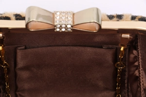 Detail of evening clutch featuring leopard print, satin lining, and diamond bow clasp