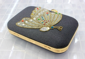 Detail of grey hard shell evening clutch featuring a colorful crystal butterfly design