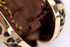 Macro detail of leopard print faux fur clutch with gold metal frame and brown fabric lining