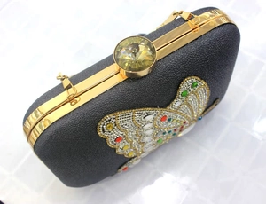 Close-up of black evening clutch with colorful crystal butterfly and large gemstone clasp