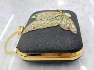 Close-up of a black glitter evening clutch with a colorful crystal butterfly ornament