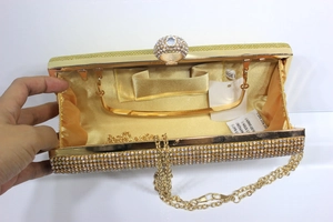 Detail of gold mermaid evening clutch showing interior satin lining and diamond chain