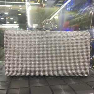 Close-up of silver rhinestone evening clutch featuring a crystal ring clasp and hard shell