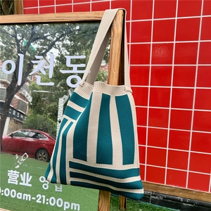 Detail of knitted tote bag showing green and beige geometric stripes and woven texture