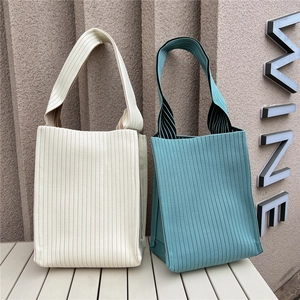 Detail of solid color knitted tote bags in beige and blue with ribbed texture