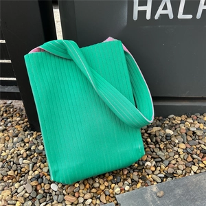 Detail of emerald green knitted tote bag with pink lining and textured pleated finish
