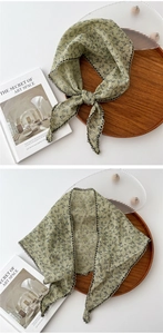 Dettaglio bandana in cotone e lino verde salvia con bordo smerlato nero e fiori neri