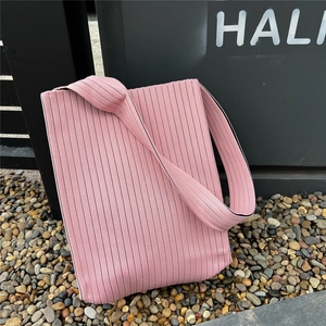 Detail of pink knitted pleated tote bag featuring black vertical stripes and a wide strap