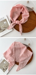 Dettaglio di un foulard in cotone rosa a fiori con pizzo bianco su vassoio di legno