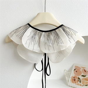 Detail of white lace fake collar with three-layer ruffled edges and black embroidery ties