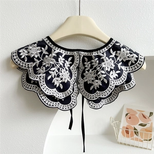 Close-up of vintage black lace shawl fake collar with white floral embroidery and ties