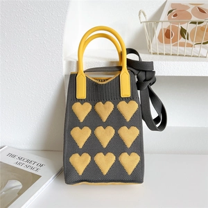 Detailed knit texture of grey mini bag with yellow hearts and round top handle