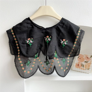 Close-up of black mesh fake collar with floral embroidery and pom-pom trim details