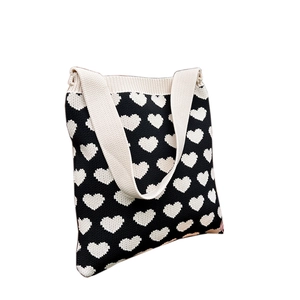 Minimalist knit tote bag with black and white heart patterns and wide shoulder straps