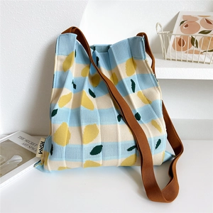 Pleated knit crossbody tote bag with blue stripes and lemon patterns on a white table