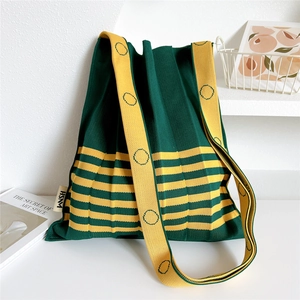 Detail view of the green pleated knit tote bag with contrasting yellow shoulder strap