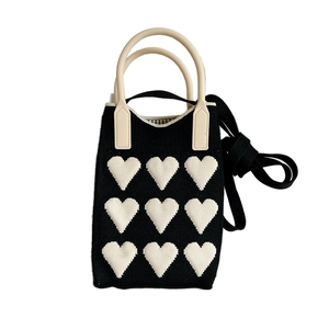 Mini knitted crossbody phone bag with black white heart pattern and top handles