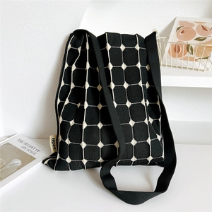 Detail of black knit tote bag showing the white grid pattern and HSNM woven label