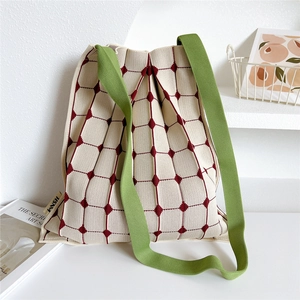 Close-up of pleated knit tote bag featuring red diamond pattern and green shoulder straps