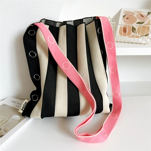 Close-up of pleated knit tote bag with black stripes and pink patterned shoulder strap