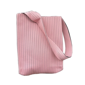 Pink knitted tote bag with vertical stripes and wide shoulder strap on white background