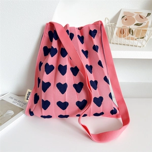Detailed macro view of the heart jacquard pattern on the pink pleated knit crossbody bag