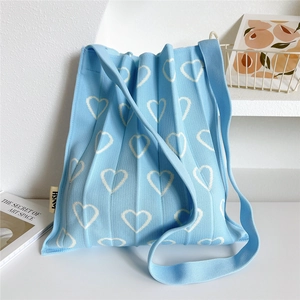 Detail of light blue pleated knit bag with white hollow heart patterns and HSM logo