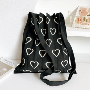Close-up of black knitted shoulder bag with cream heart jacquard and pleated texture