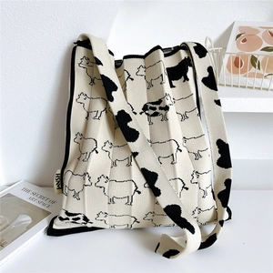 Close-up of cream knit tote bag featuring cow print pattern and woven HSM brand label