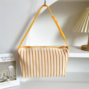 Close-up of yellow and beige striped knitted handbag with adjustable shoulder strap
