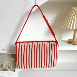 Detail of red and white striped knit tote bag with red strap and zipper closure