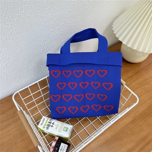 Close-up of klein blue knit tote bag featuring red hearts in a white metal basket