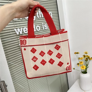 Detail of red and white knit tote bag featuring woven heart and smiley face symbols
