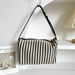 Close-up of a striped knit shoulder bag featuring a black and white texture and zip closure