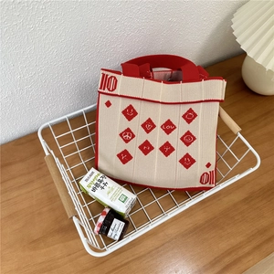 Detail of red and white knit tote bag with heart patterns in a cozy wooden desk setting