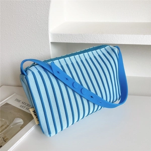Detail of blue striped knitted shoulder bag featuring adjustable silicone strap and side tag