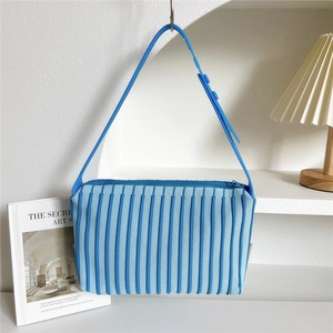 Close-up of sky blue pleated knit tote bag with adjustable strap and zip closure
