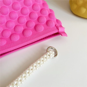 Magenta knitted bubble bucket bag with pearl strap and silver metal rings on white background
