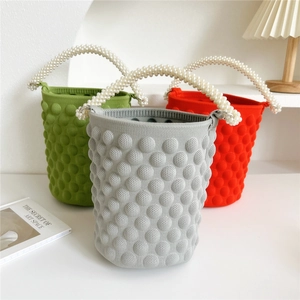 Three colorful knitted bucket bags with elegant pearl handles in green, grey, and orange