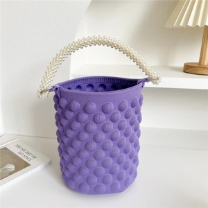 Detail of purple knitted bucket bag with bubble texture and elegant white pearl handle