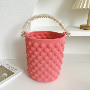 Detail of pink knitted bucket bag with bubble texture and white pearl bead handle