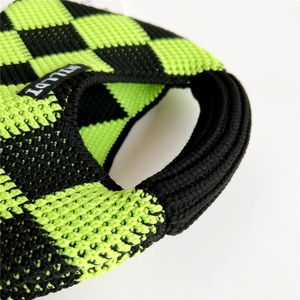 Detail view of the thick checkered knit fabric and black woven label on a trendy handbag
