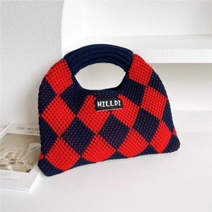 Detailed texture of a red and blue checkered knitted handbag with woven brand label