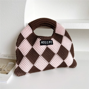 Close-up of knit tote bag showing argyle pattern and woven brand label detail