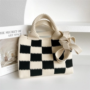Détail du sac cabas en maille à damier noir et blanc avec ruban et texture tissée