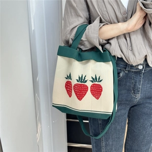 Knitted strawberry tote bag with green handles and long strap for shoulder or crossbody use