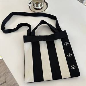 Flat lay of a black and white striped knit tote bag with shoulder strap and floral coffee cup